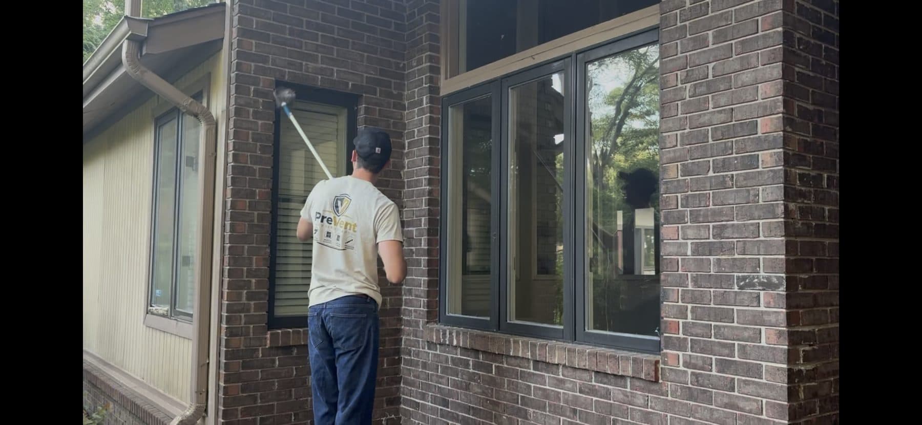 Washing an upper window on a brick home with a water-fed pole